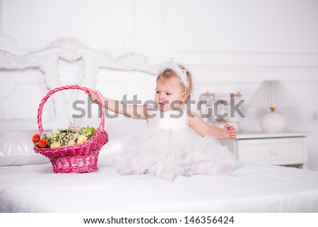 girl in a beautiful dress on a bed with a basket of flowers