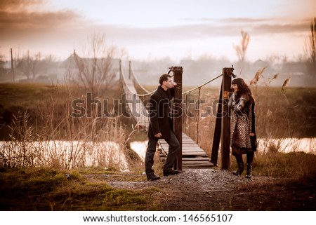 A love story. A man and a woman near the bridge. Love relationship. Autumn sunset.