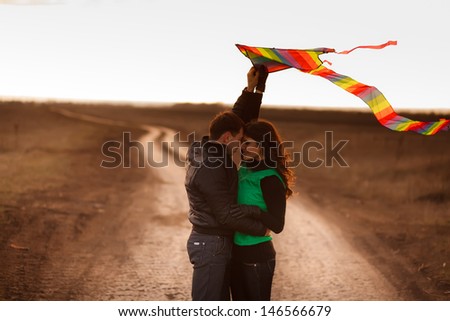 A love story. A man and a woman on autumn road running with a kite. Love and relationships. Autumn sunset.