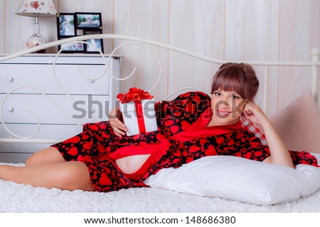 beautiful pregnant woman on a bed with a gift