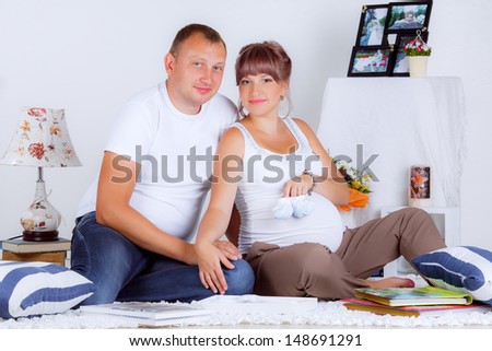 beautiful pregnant woman with her husband looking pictures. smiling. memories. happy family
