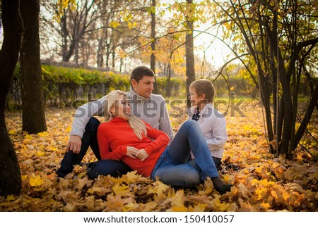 wonderful parents and son in an autumn garden. yellow autumn leaves, autumn sunset