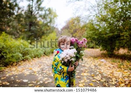 little boy in the autumn park with a large bouquet