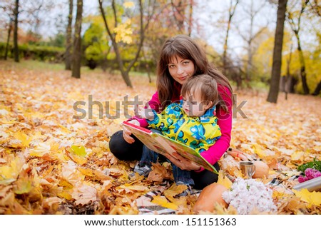 Mom and son 3 years reading a book outdoors