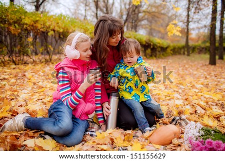 Happy mother with her children on a picnic. family tea party in the garden in autumn