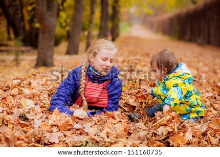 happy children throw autumn leaves in autumn park