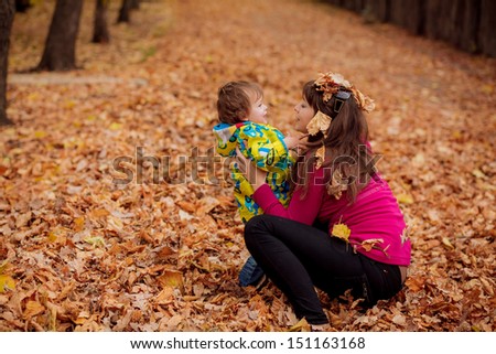 Children 3 years of age throws autumn leaves. mother next to her son