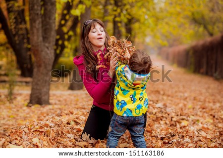 Mom and son throw autumn leaves
