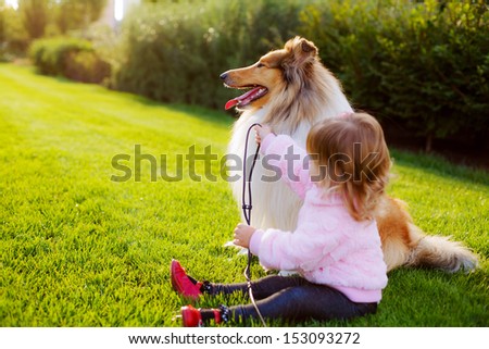 a beautiful little girl and a dog in the light of the setting sun
