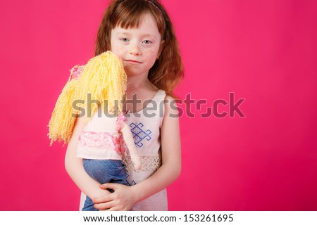 beautiful girl with red hair hugging her doll. sad sight