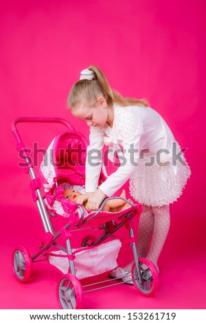 beautiful girl with blond hair lays the doll in the stroller