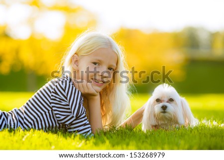 blonde girl with a dog lap dog. look in the picture. autumn landscape