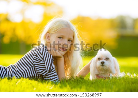 blonde girl with a dog lap dog. look in the picture. autumn landscape. close-up