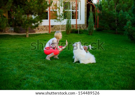 beautiful young blond woman trains dogs in the garden. Dalmatian breed and Laika