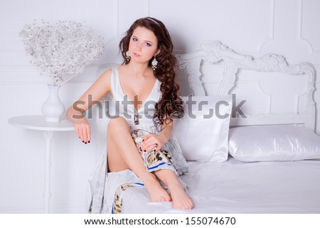 portrait of a beautiful girl on the bed in the bedroom. Female young model. Studio , gray background . Fashion model studio poses.