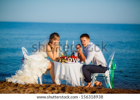 happy couple at the table by the sea. looking at the camera