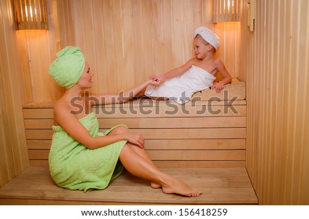 happy mother with her daughter in the sauna. smile and look at each other