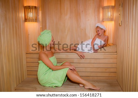 beautiful mother and daughter in the sauna. smile and look at each other