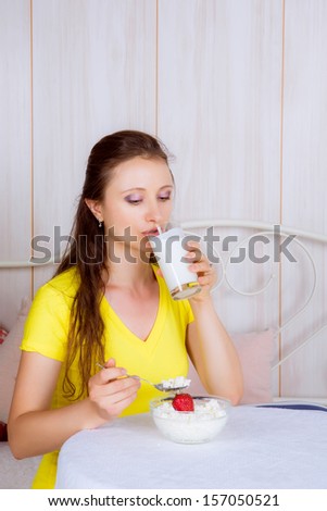 beautiful girl at the table eating dairy products and drinking milk