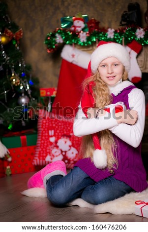 girl sitting by the fireplace and Christmas tree.   Christmas