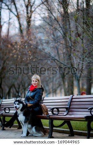 beautiful girl and dog Huskies walking around the city, the owner of the dog sitting on the bench