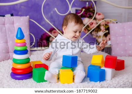 portrait of a beautiful girl. child age 7 months playing with colorful cubes
