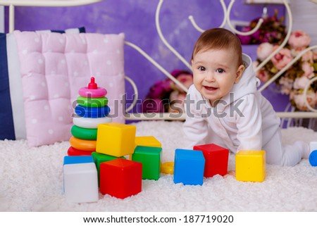 portrait of a beautiful girl age 7 months playing with colorful cubes