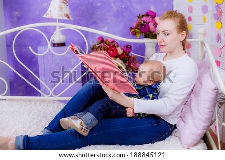 Happy mom and baby in the room. Mom reading a book to the child. studio photoshoot