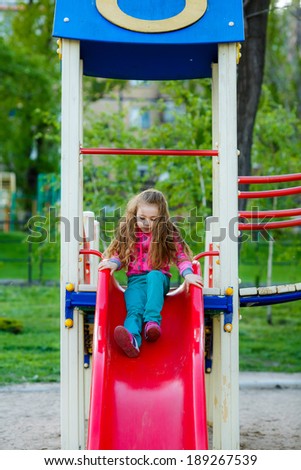 happy little girl on the slide at the playground