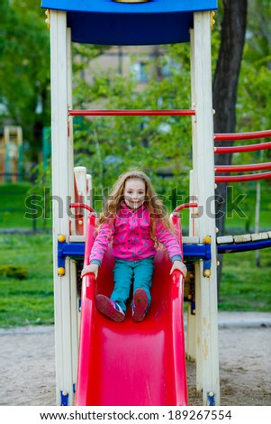 happy little girl on the slide at the playground