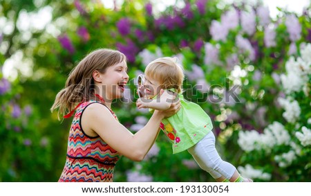 Mom throws baby. lilac bloom, mother and child communication, joy, happiness, emotion, summer