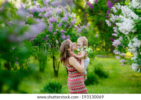 Mom throws baby. lilac bloom, mother and child communication, joy, happiness, emotion, summer