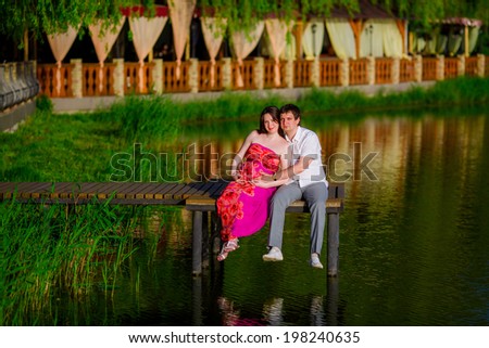 Happy pregnant woman with her husband relaxing on the lake