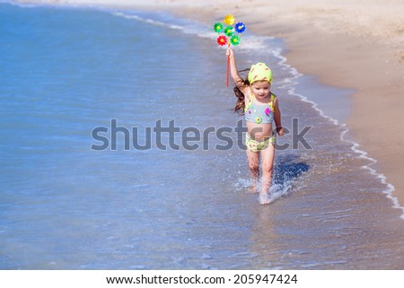 girl with toy runs along the beach, summer, happiness, wind, waves