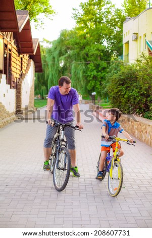 Dad and son at the park and ride on bicycles