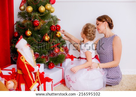 happy mother and daughter in a room near the Christmas tree. red concept. gifts