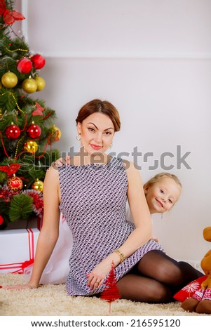 Christmas concept. happy mother and daughter in a room near the Christmas tree. red concept. gifts