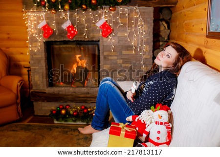 beautiful woman near the fireplace in the winter house.   holidays