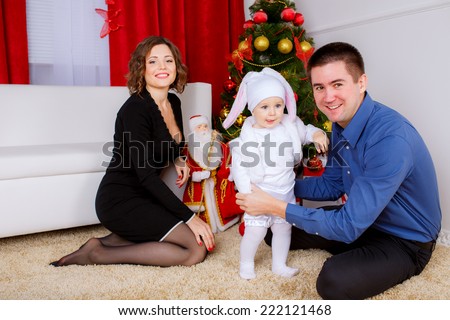 Happy parents with their son near Christmas tree. rabbit costume, new year gifts