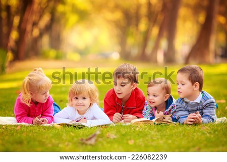 children in nature. reading a book outdoors lying on the grass