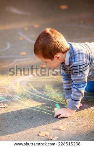 happy children draw with crayons on the pavement in the park