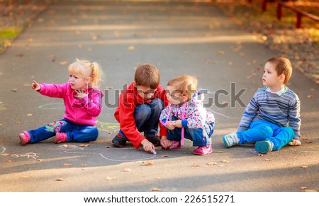 children draw colored chalk on the asphalt in the park