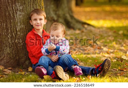 Happy brother and sister on a glade in park