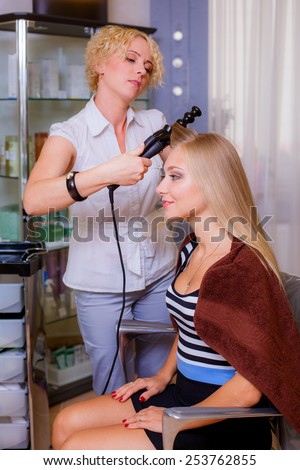 Beautiful young hairdresser giving a new haircut to female customer at parlor, hair care