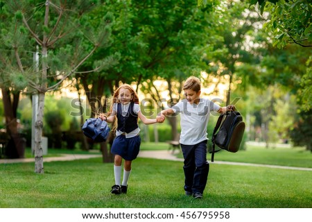 happy schoolchildren running in the park after school. waving backpacks. September 1