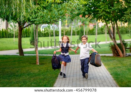 happy schoolchildren running in the park after school. waving backpacks. September 1