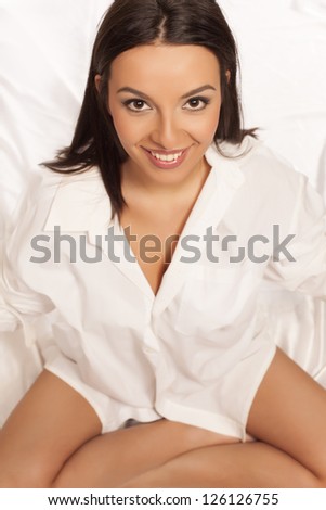 pretty smiling brunette in a white men\'s shirt on white background