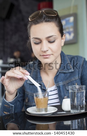 girl pours sugar into her coffee in a restaurant
