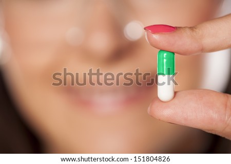 woman scientist with a smile showing a capsule pill with a focus on the foreground