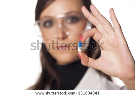 serious woman scientist shows a capsule pill with a focus on the foreground